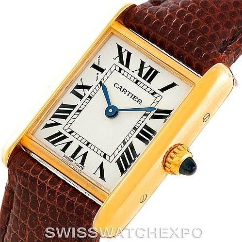 The image shows a close-up view of a Cartier Tank Louis W1529856 Women's Yellow Gold Silver Dial W1529856 Women's Yellow Gold Silver Dial watch, highlighting its rectangular face, Roman numerals, blue hands, gold casing, and brown strap.
