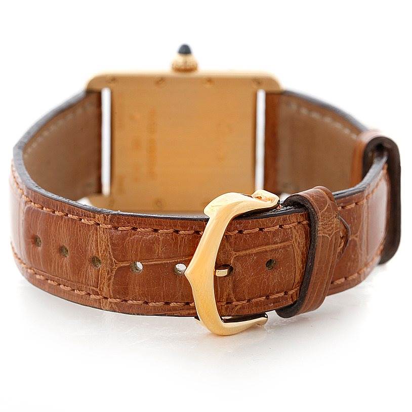 The image shows the back angle of a Tank Louis watch by Cartier, highlighting the brown leather strap and gold buckle.