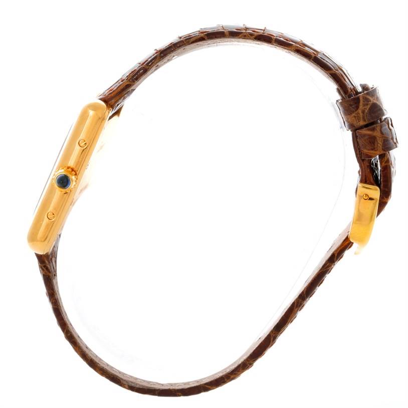 This side-angle view of the Cartier Tank Louis W1529856 Women's Yellow Gold Silver Dial W1529856 Women's Yellow Gold Silver Dial watch showcases its slim profile, crown, case, and leather strap.