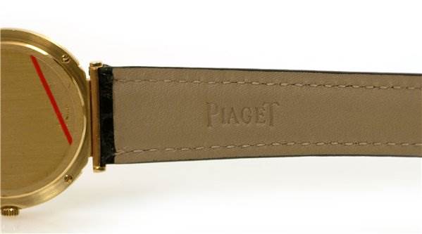 This image shows the side view of the bezel and a portion of the strap embossed with "Piaget 8673 Men's Yellow Gold Champagne Dial 8673 Men's Yellow Gold Champagne Dial" from the Mens 18k Yellow Gold Polo 8673 Unworn Watch by Piaget 8673 Men's Yellow Gold Champagne Dial 8673 Men's Yellow Gold Champagne Dial.