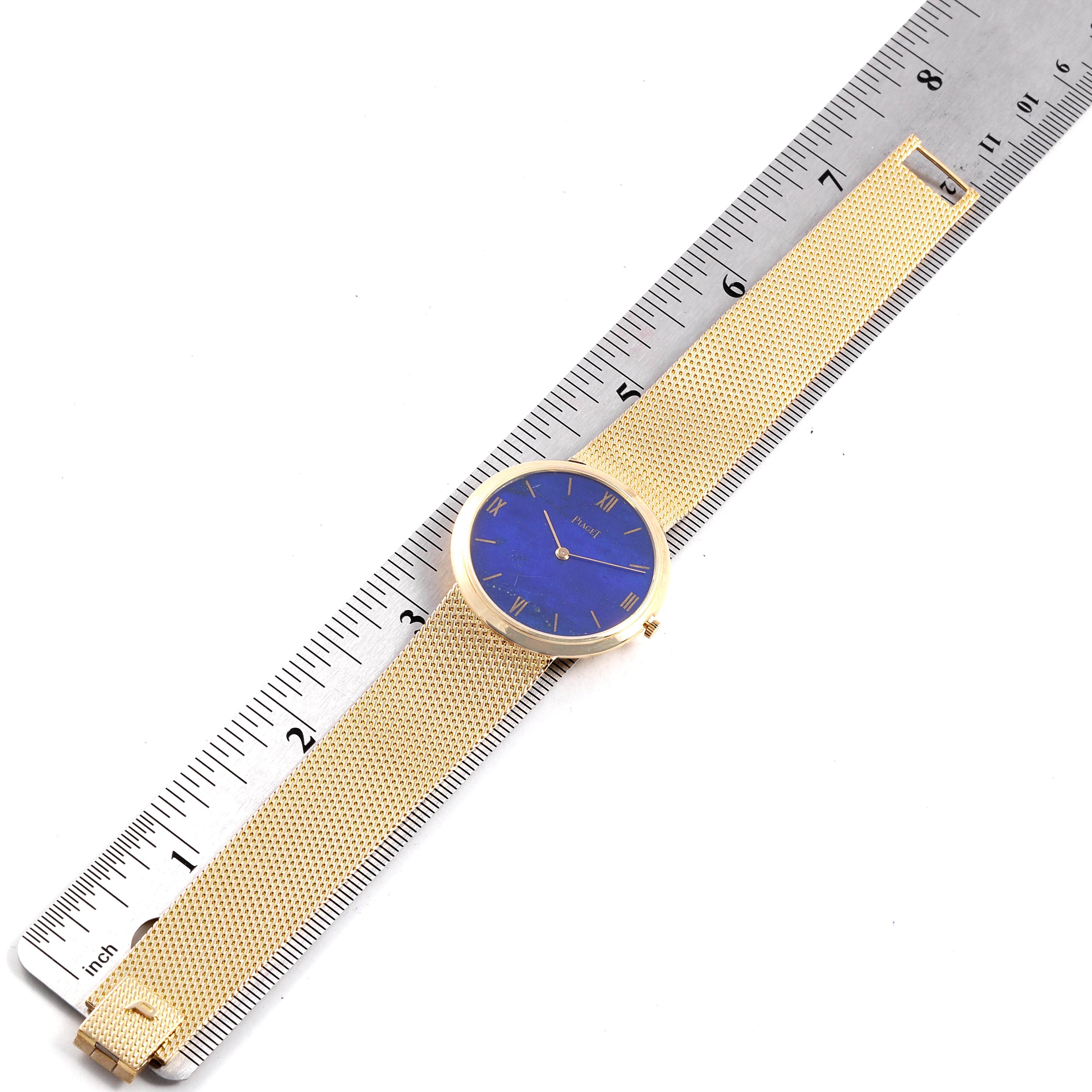 The image shows the Piaget 902B11 Men
s Yellow Gold Blue Dial 902B11 Men
s Yellow Gold Blue Dial 902B11 model watch, featuring an 18k yellow gold band and lapis lazuli dial, viewed from above next to a ruler.