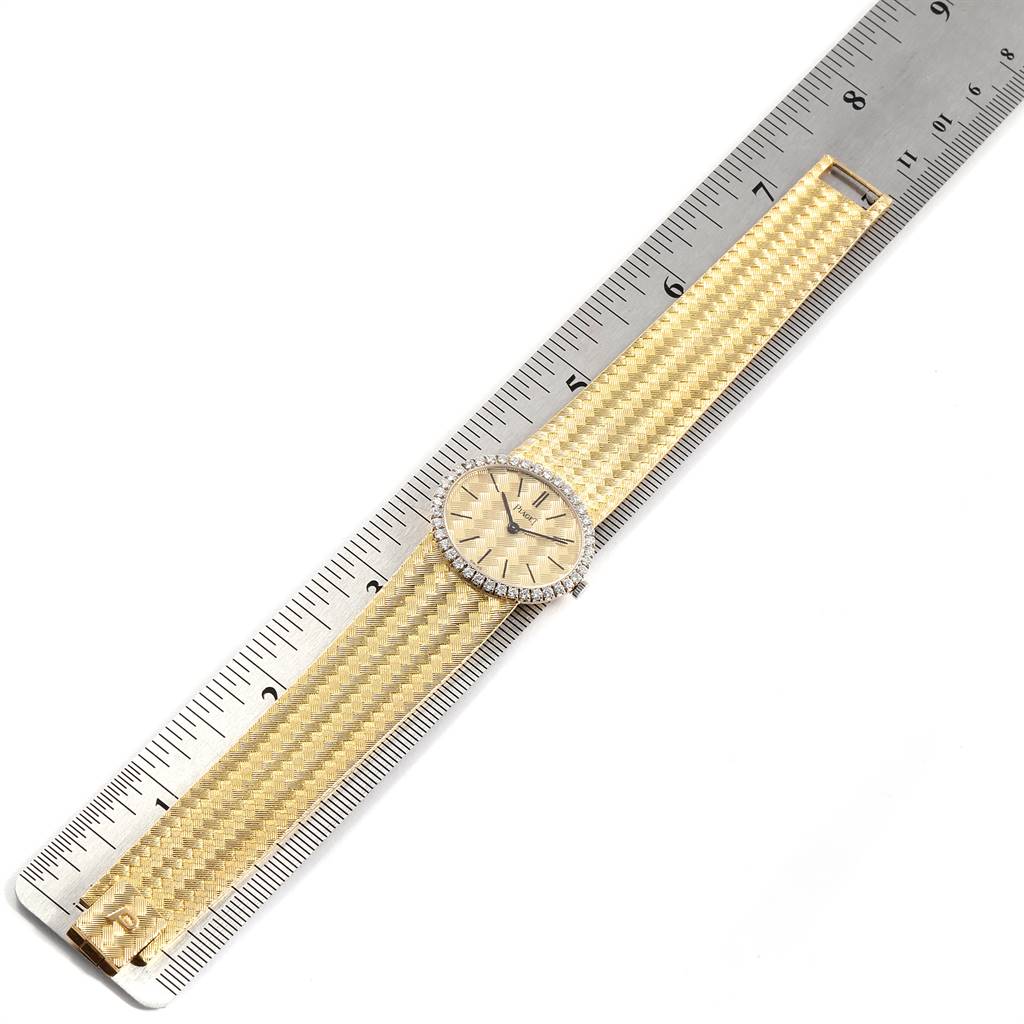 This image shows a Piaget 9806 Women
s Yellow Gold Champagne Dial 9806 Women
s Yellow Gold Champagne Dial 9806 18k Yellow Gold Diamond Ladies Watch laid flat next to a ruler, displaying the entire band and face.