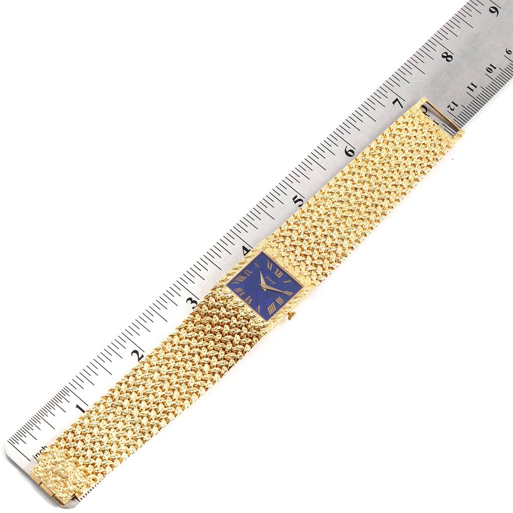 The image shows a top-down view of a Piaget 9352 Men's Yellow Gold Blue Dial 9352 Men's Yellow Gold Blue Dial 9352 model watch, featuring an 18k yellow gold band and blue lapis lazuli dial, alongside a ruler.