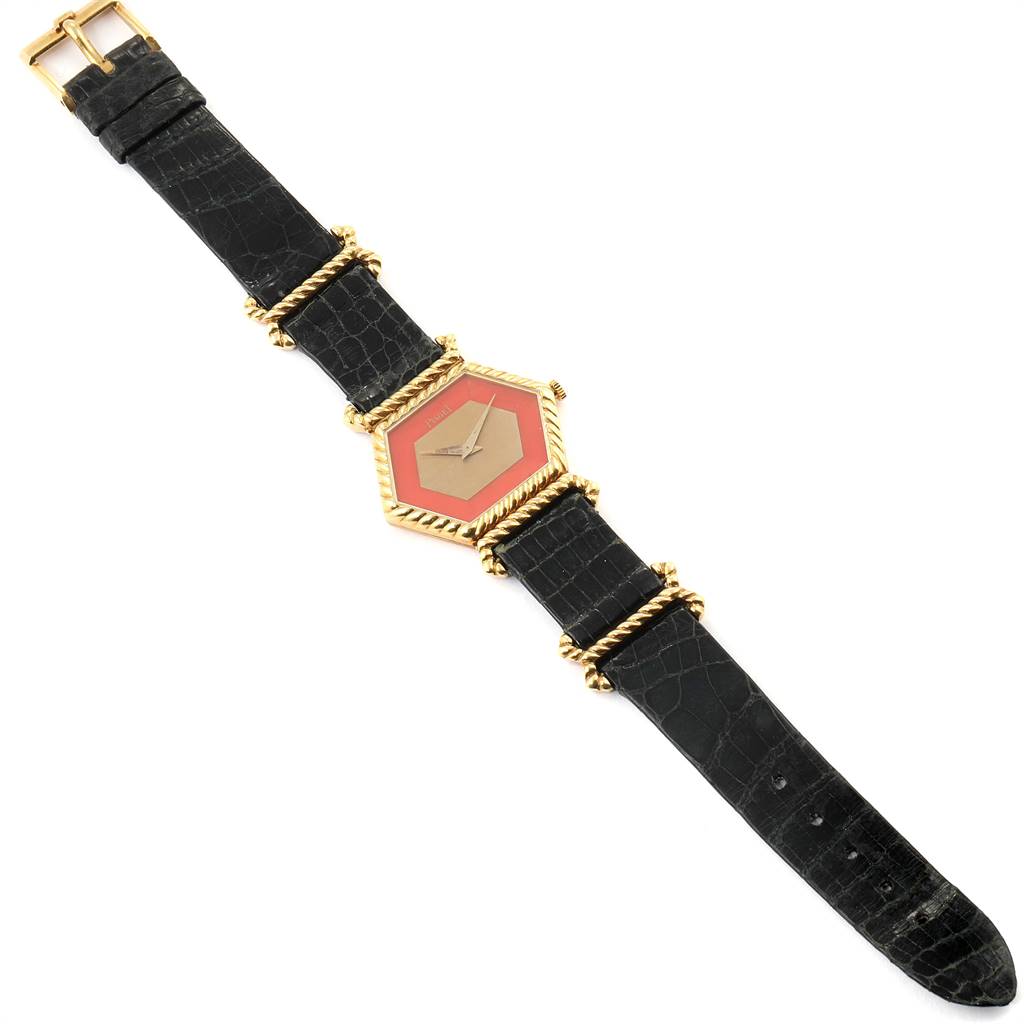 This Piaget 9559 Women's Yellow Gold Pink Dial 9559 Women's Yellow Gold Pink Dial 9559 model watch is shown from a top-down angle, displaying the 18K yellow gold hexagonal coral dial and black strap.