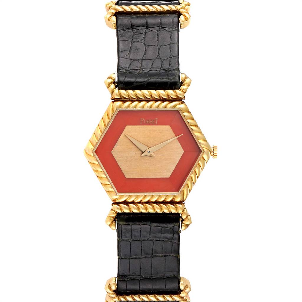 The image shows a Piaget 9559 Women's Yellow Gold Pink Dial 9559 Women's Yellow Gold Pink Dial 9559 model vintage ladies watch with an 18K yellow gold hexagonal case, coral dial, and black leather strap.