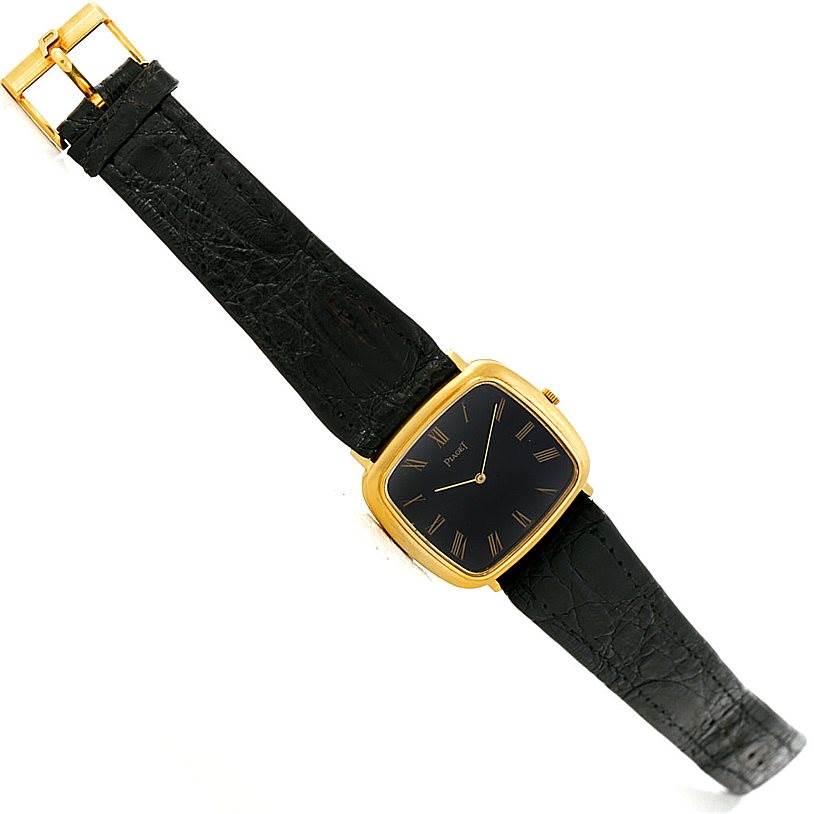 The image shows a top-down view of the Piaget Men's Yellow Gold Black Dial Men's Yellow Gold Black Dial 18K Yellow Gold Cushion Shape Mechanical Men's Watch, highlighting the face and black strap.