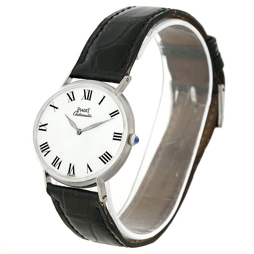 This image shows a Piaget 12501 Men's White Gold White Dial 12501 Men's White Gold White Dial 12501 model watch from a side angle, highlighting the white gold case, white dial, Roman numerals, and black leather strap.