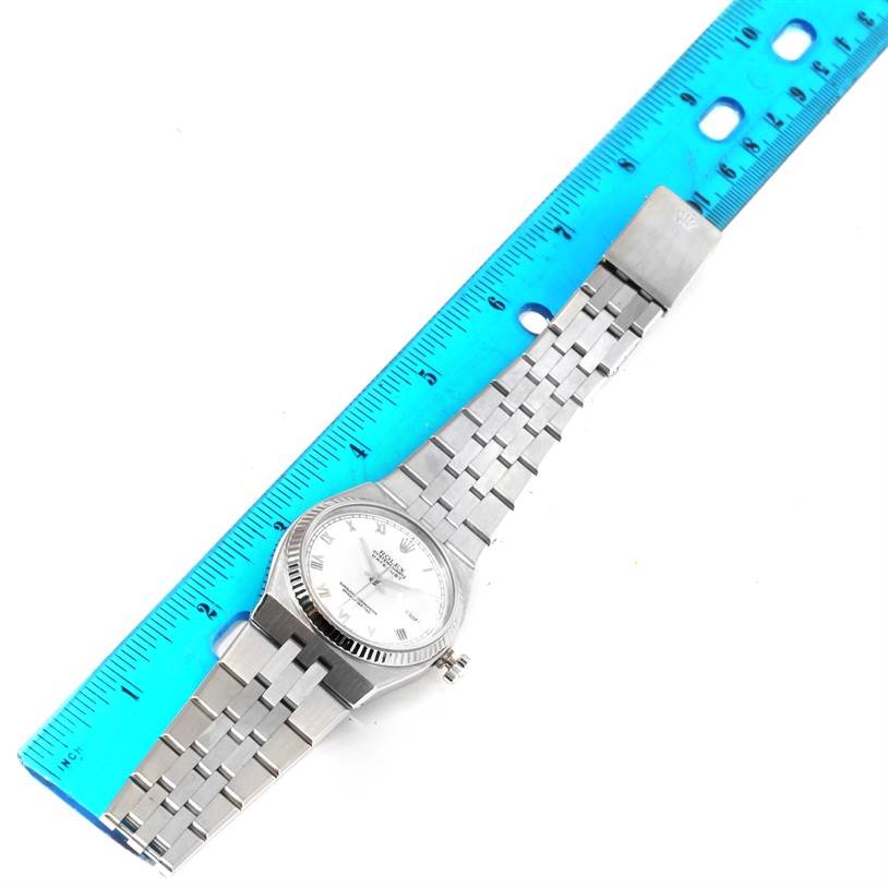 The Rolex Oysterquartz 17014 Men's Stainless Steel White Dial 17014 Men's Stainless Steel White Dial watch is shown from an overhead angle, including the face, bezel, crown, and metal bracelet alongside a ruler.