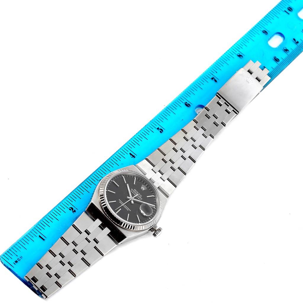 The image shows a top view of a Rolex Oysterquartz 17014 Men's Stainless Steel White Dial 17014 Men's Stainless Steel White Dial watch, including its face, bracelet, and clasp, next to a blue ruler for scale.