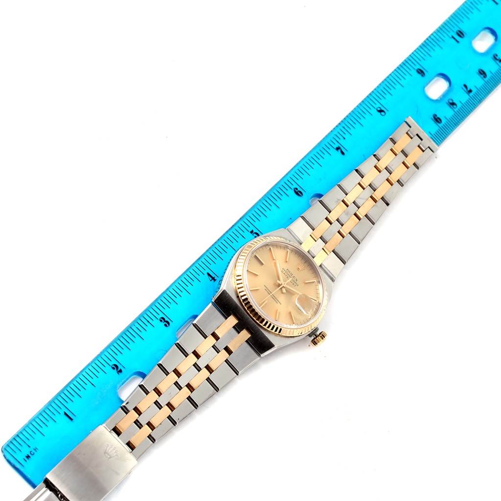 The Oysterquartz model by Rolex is shown from a top-down angle, displayed alongside a blue ruler for size reference.