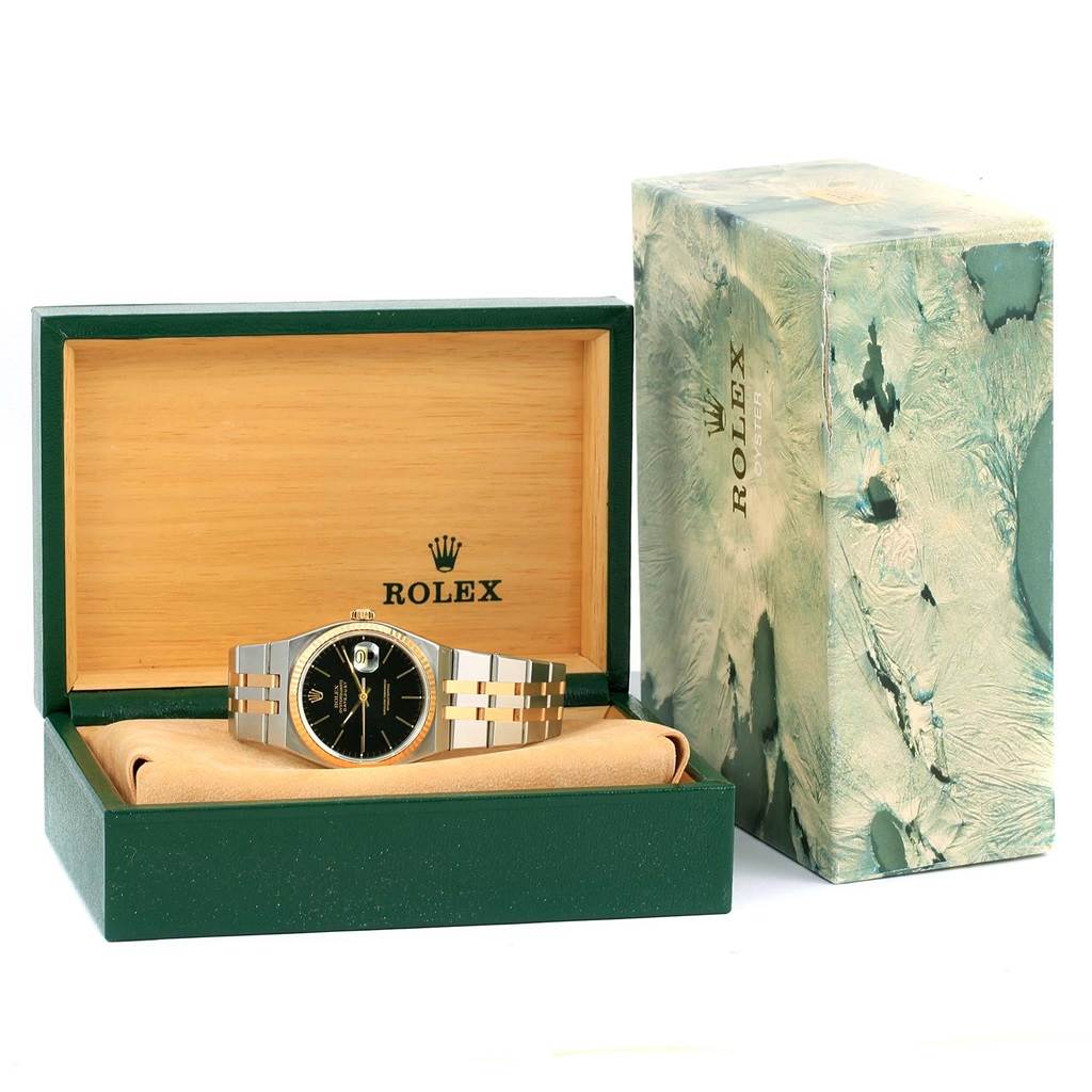 The Rolex Oysterquartz 17013 Men
s Stainless Steel Black Dial 17013 Men
s Stainless Steel Black Dial watch is shown in a green and wooden box, accompanied by its marble-textured packaging.