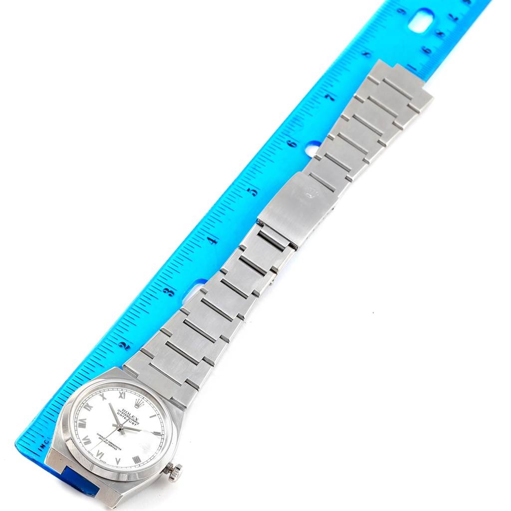 The image shows a Rolex Oysterquartz 17000 Men's Stainless Steel White Dial 17000 Men's Stainless Steel White Dial watch lying flat on a blue ruler, displaying its face and metal band.