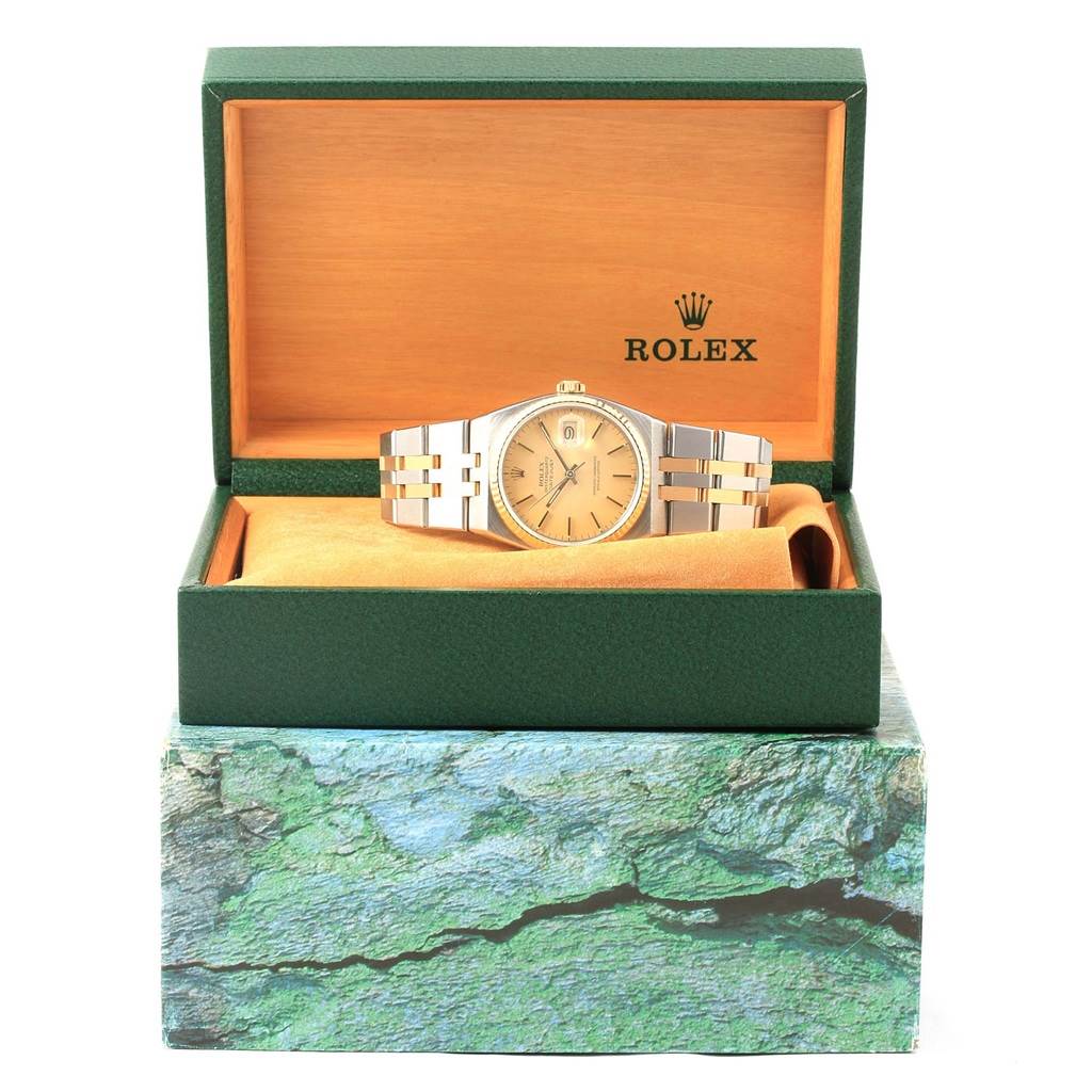 The Rolex Oysterquartz 17013 Men's Stainless Steel Champagne Dial 17013 Men's Stainless Steel Champagne Dial watch is shown from the front, displayed in an open green and beige box. 