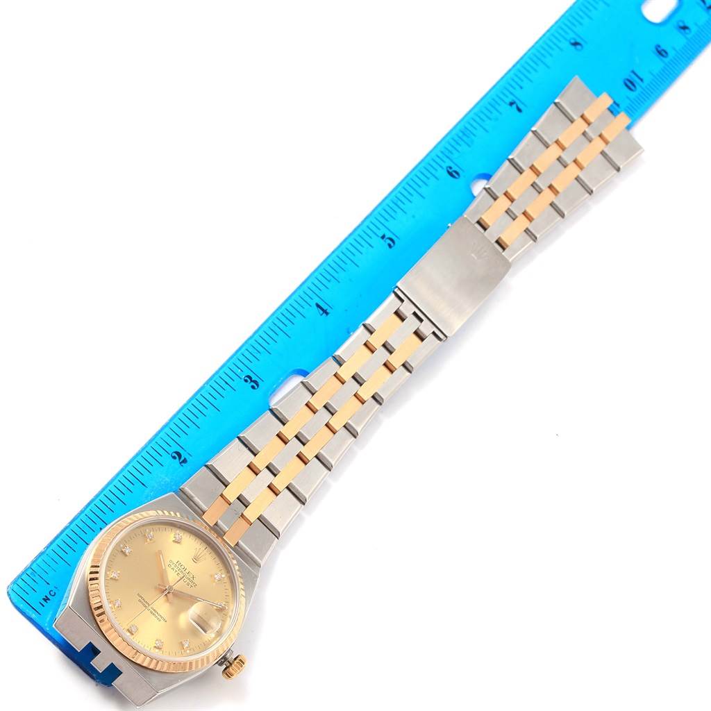 The image shows a Rolex Oysterquartz 17013 Men
s Stainless Steel Champagne Dial 17013 Men
s Stainless Steel Champagne Dial watch, positioned flat alongside a blue ruler measuring its length.