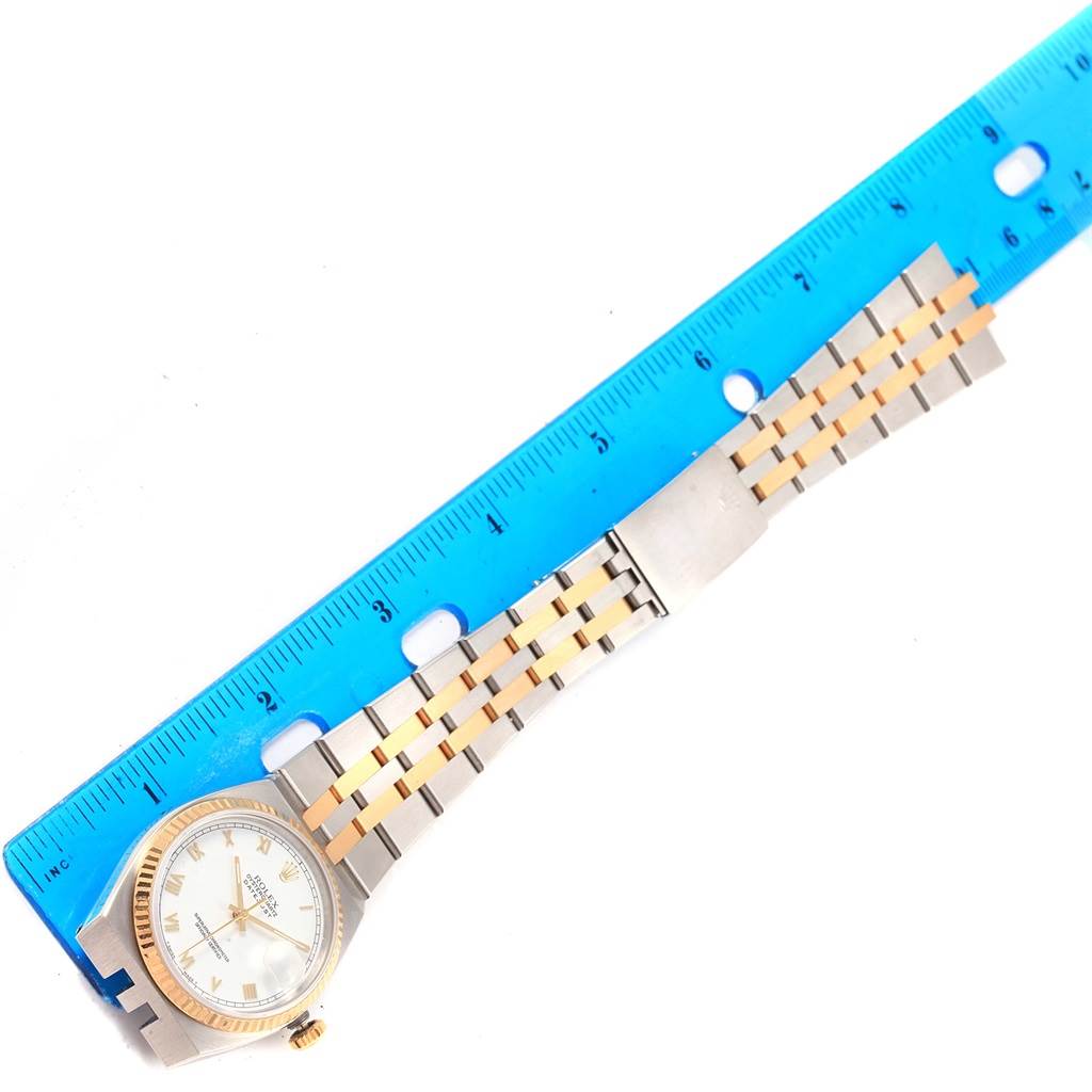 The image shows a Rolex Oysterquartz 17013 Men's Stainless Steel White Dial 17013 Men's Stainless Steel White Dial watch lying flat, with its two-tone bracelet and part of the dial visible, next to a blue ruler.