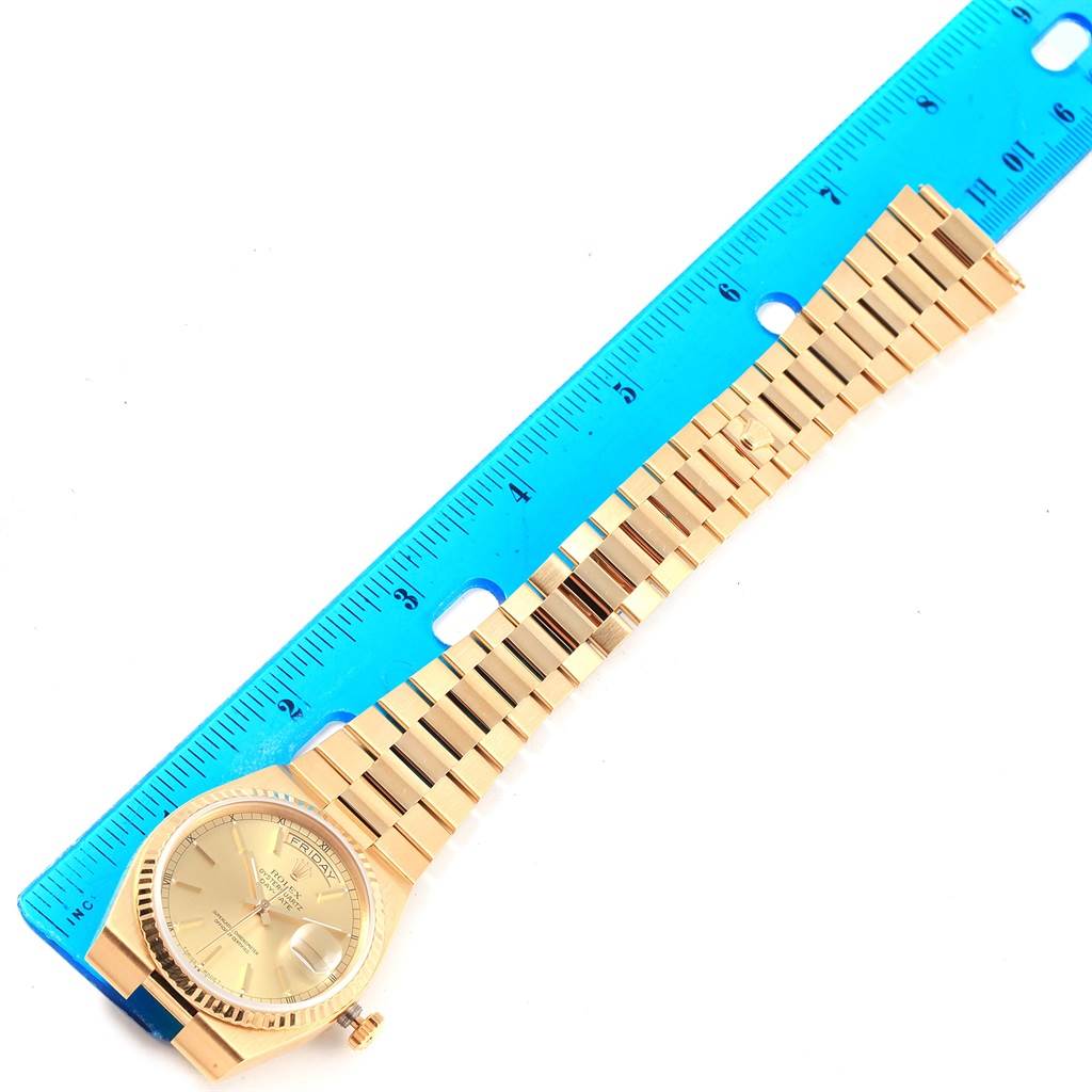 The image shows a Rolex Oysterquartz 19018 Men's Yellow Gold Champagne Dial 19018 Men's Yellow Gold Champagne Dial watch laid flat with its full-length band next to a blue ruler for scale.