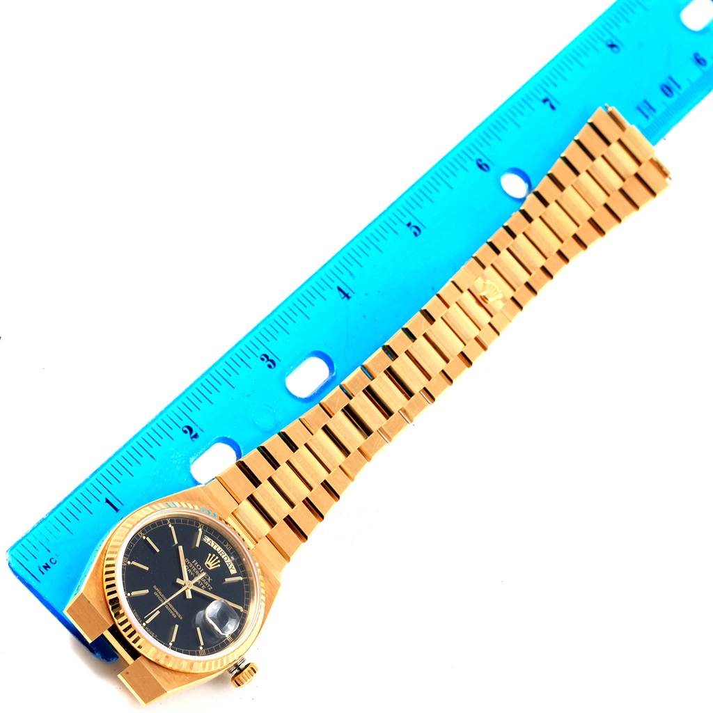 The image shows a top-down view of a Rolex Oysterquartz 19018 Men's Yellow Gold Black Dial 19018 Men's Yellow Gold Black Dial watch, highlighting its black dial, gold case, and integrated bracelet alongside a ruler.