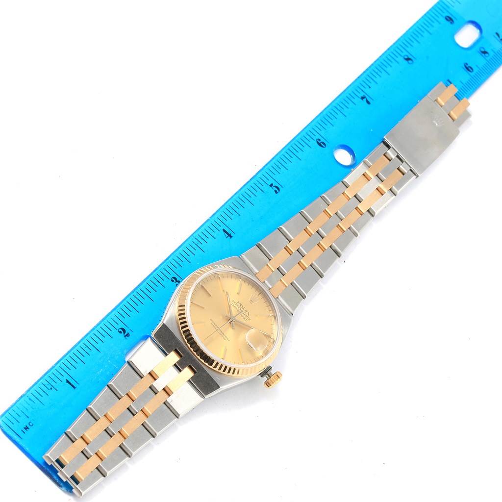 The image shows an overhead view of a Rolex Oysterquartz 17013 Men's Stainless Steel Champagne Dial 17013 Men's Stainless Steel Champagne Dial watch, with the band fully extended next to a ruler for size reference.