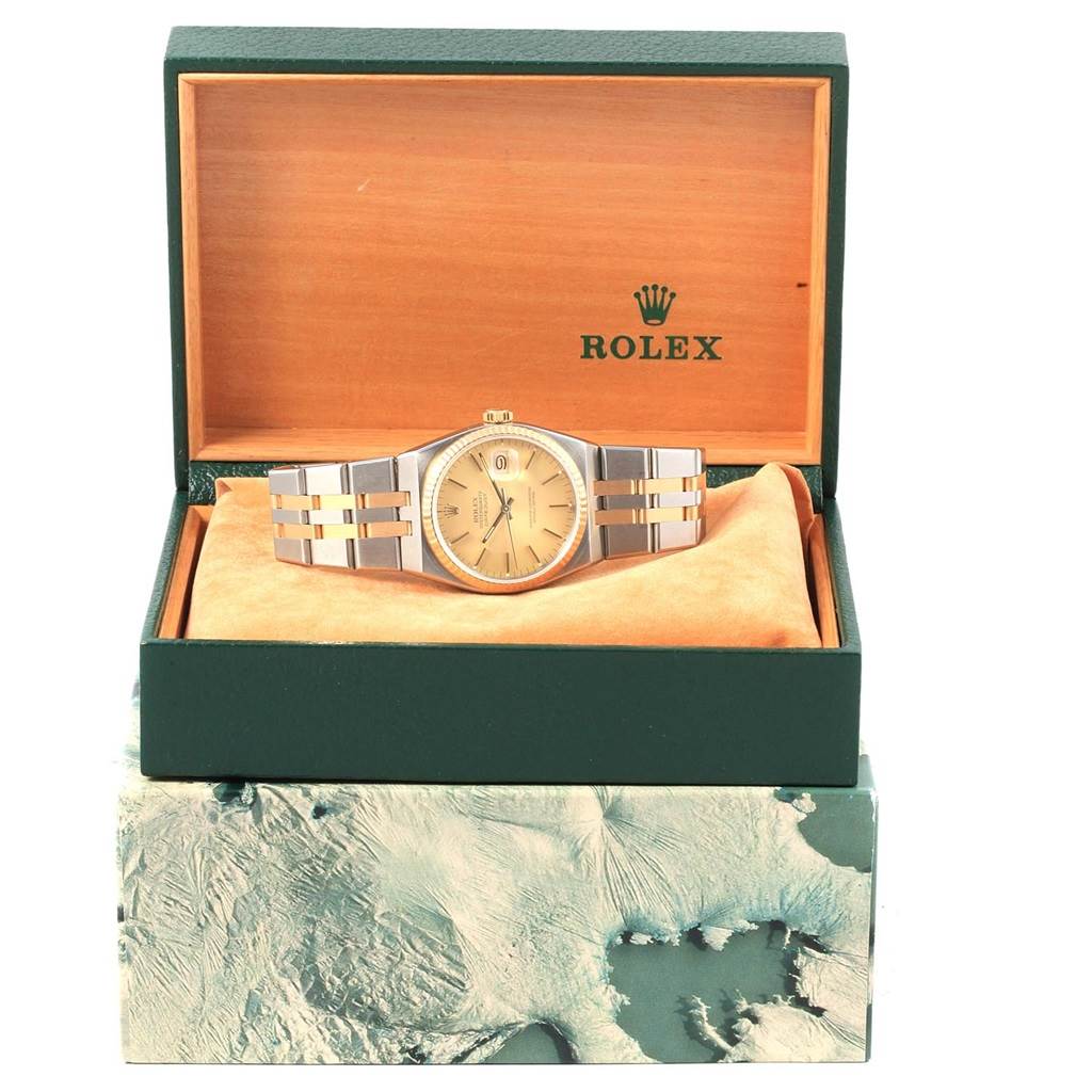 The image shows a frontal view of the Rolex Oysterquartz 17013 Men's Stainless Steel Champagne Dial 17013 Men's Stainless Steel Champagne Dial watch in its open green and wood display box.