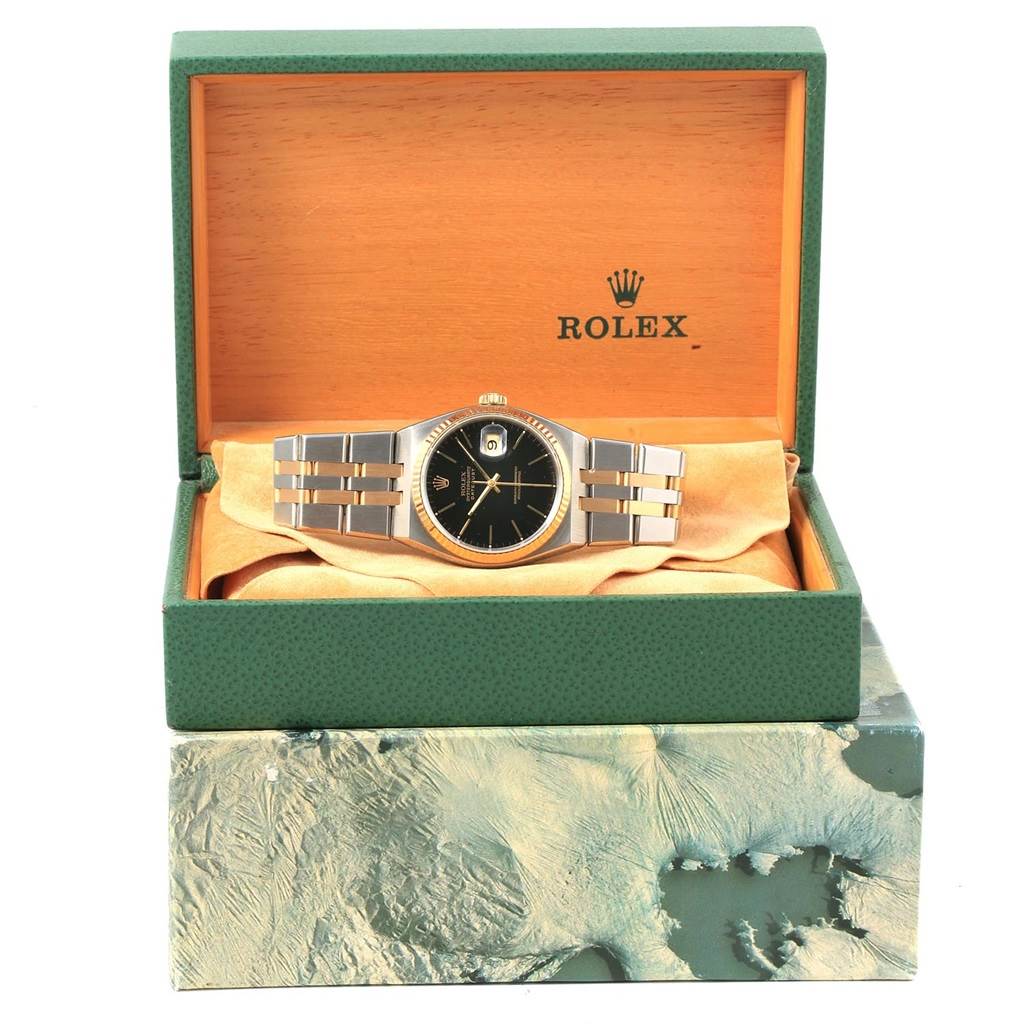 The Rolex Oysterquartz 17013 Men's Stainless Steel Black Dial 17013 Men's Stainless Steel Black Dial watch is shown front-on inside its open green and tan display box.