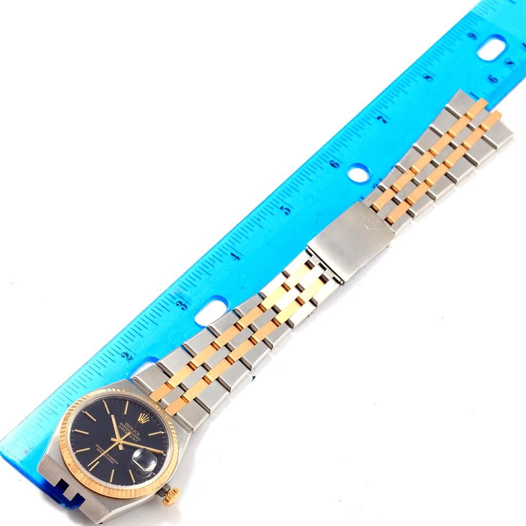 The image shows the Rolex Oysterquartz 17013 Men's Stainless Steel Black Dial 17013 Men's Stainless Steel Black Dial watch placed next to a ruler, displaying its face and band from an overhead angle.