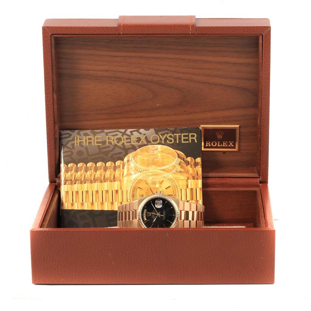 The image shows a Rolex Oysterquartz 19018 Men
s Yellow Gold Black Dial 19018 Men
s Yellow Gold Black Dial watch placed in its box with a booklet behind it, viewed from the front.