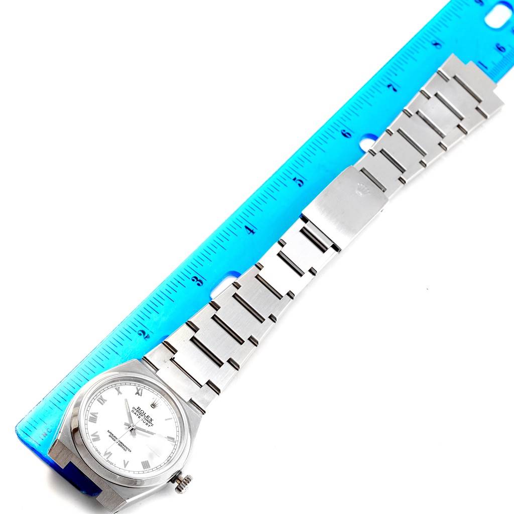 The image shows a top-down view of a Rolex Oysterquartz 17000 Men's Stainless Steel White Dial 17000 Men's Stainless Steel White Dial watch with its bracelet next to a blue ruler.