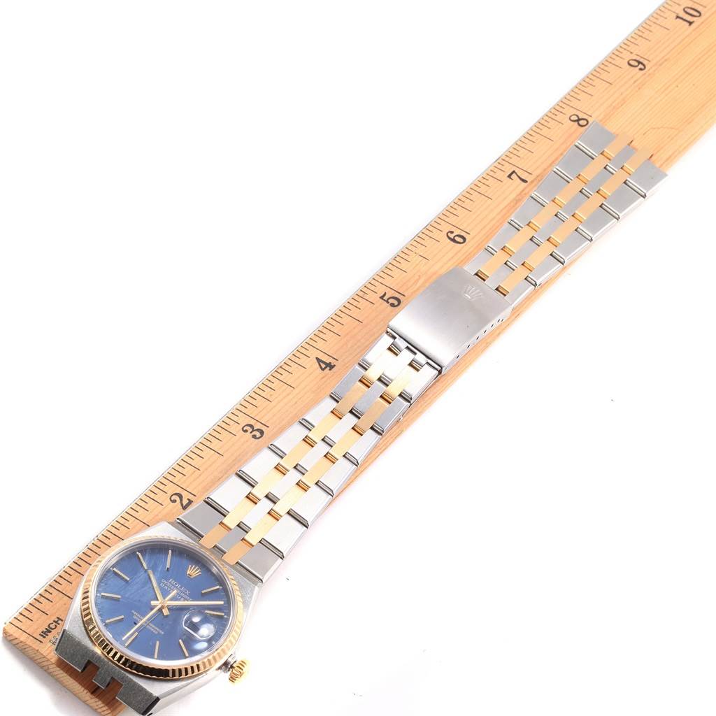 The Rolex Oysterquartz 17013 Men
s Stainless Steel Blue Dial 17013 Men
s Stainless Steel Blue Dial watch is shown from a top angle, highlighting the face, bezel, and full bracelet on a ruler.