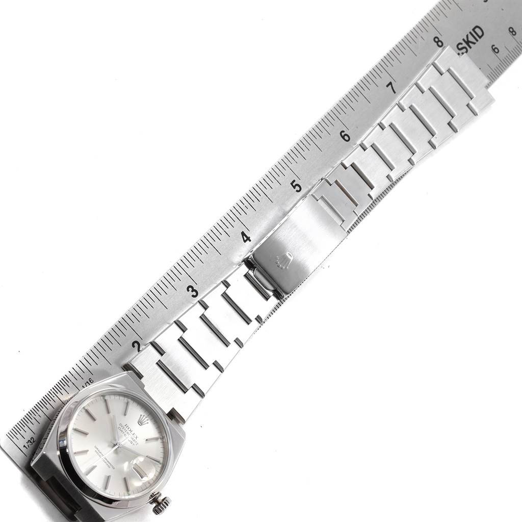 The image shows a Rolex Oysterquartz 17000 Men
s Stainless Steel Silver Dial 17000 Men
s Stainless Steel Silver Dial watch from above, featuring the dial, case, and bracelet laid out alongside a ruler.
