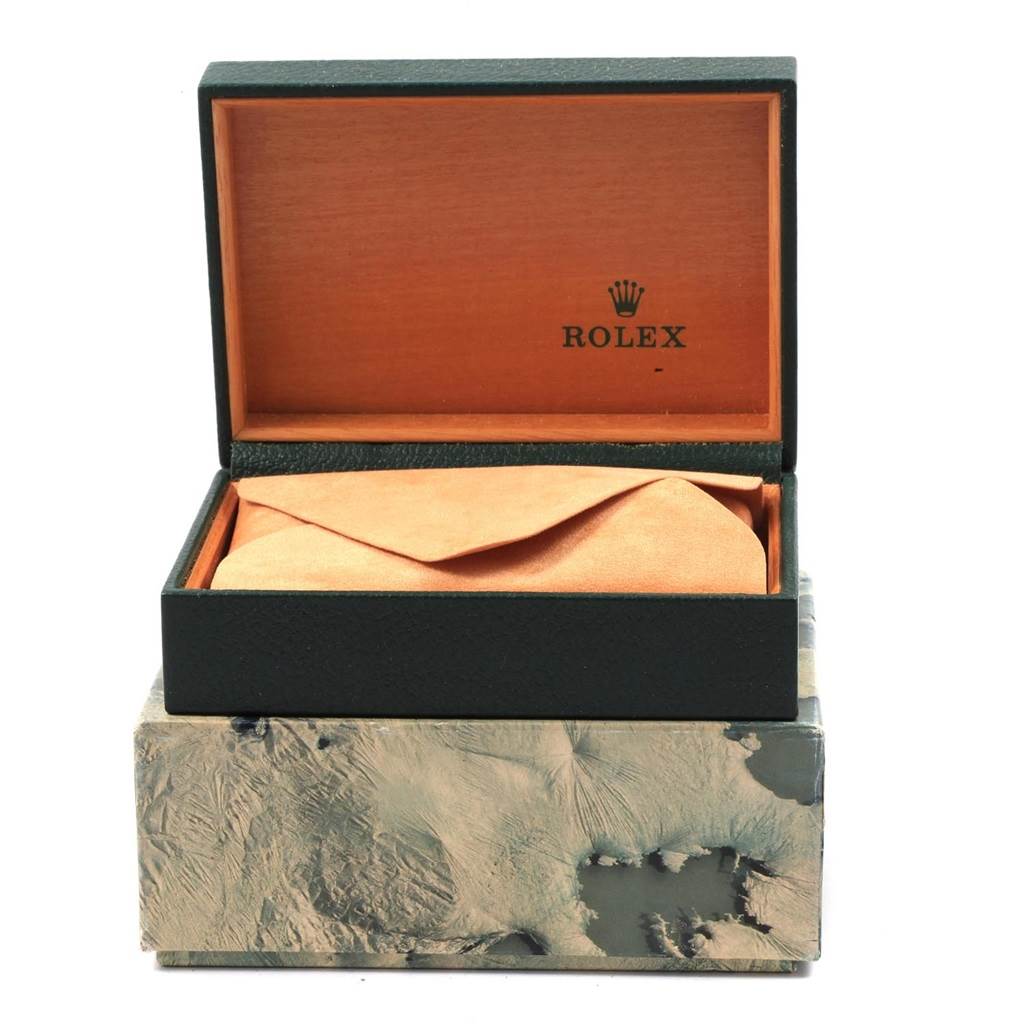 The image shows an open Rolex box containing an Oysterquartz model, with the watch wrapped in an orange cloth.