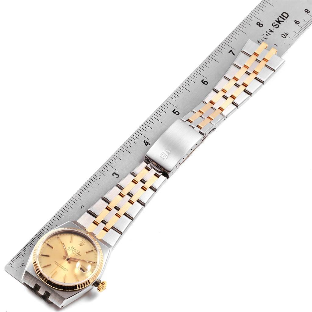 The image shows a Rolex Oysterquartz 17013 Men
s Stainless Steel Champagne Dial 17013 Men
s Stainless Steel Champagne Dial watch with a two-tone metal bracelet laid out flat alongside a ruler.