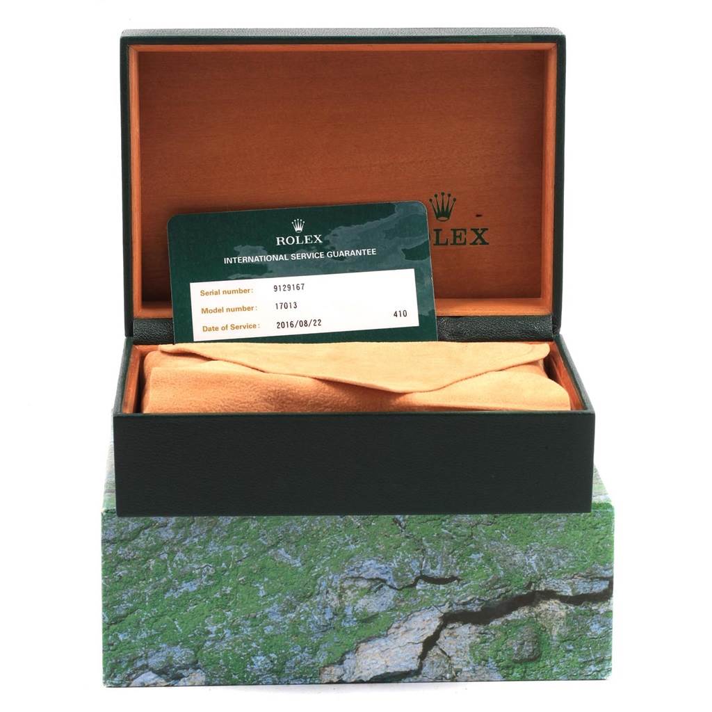 The image shows a Rolex Oysterquartz 17013 Men
s Stainless Steel Champagne Dial 17013 Men
s Stainless Steel Champagne Dial model 17013 watch box with an international service guarantee card placed inside.