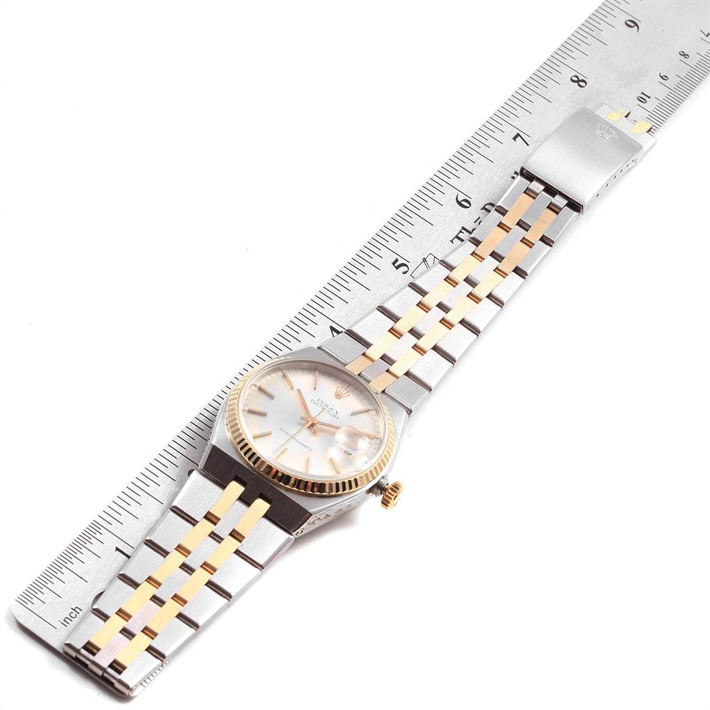 The Rolex Oysterquartz 21993 Men
s Stainless Steel Silver Dial 21993 Men
s Stainless Steel Silver Dial watch is shown lying flat, aligned with a ruler, displaying the watch face, bracelet, and clasp.