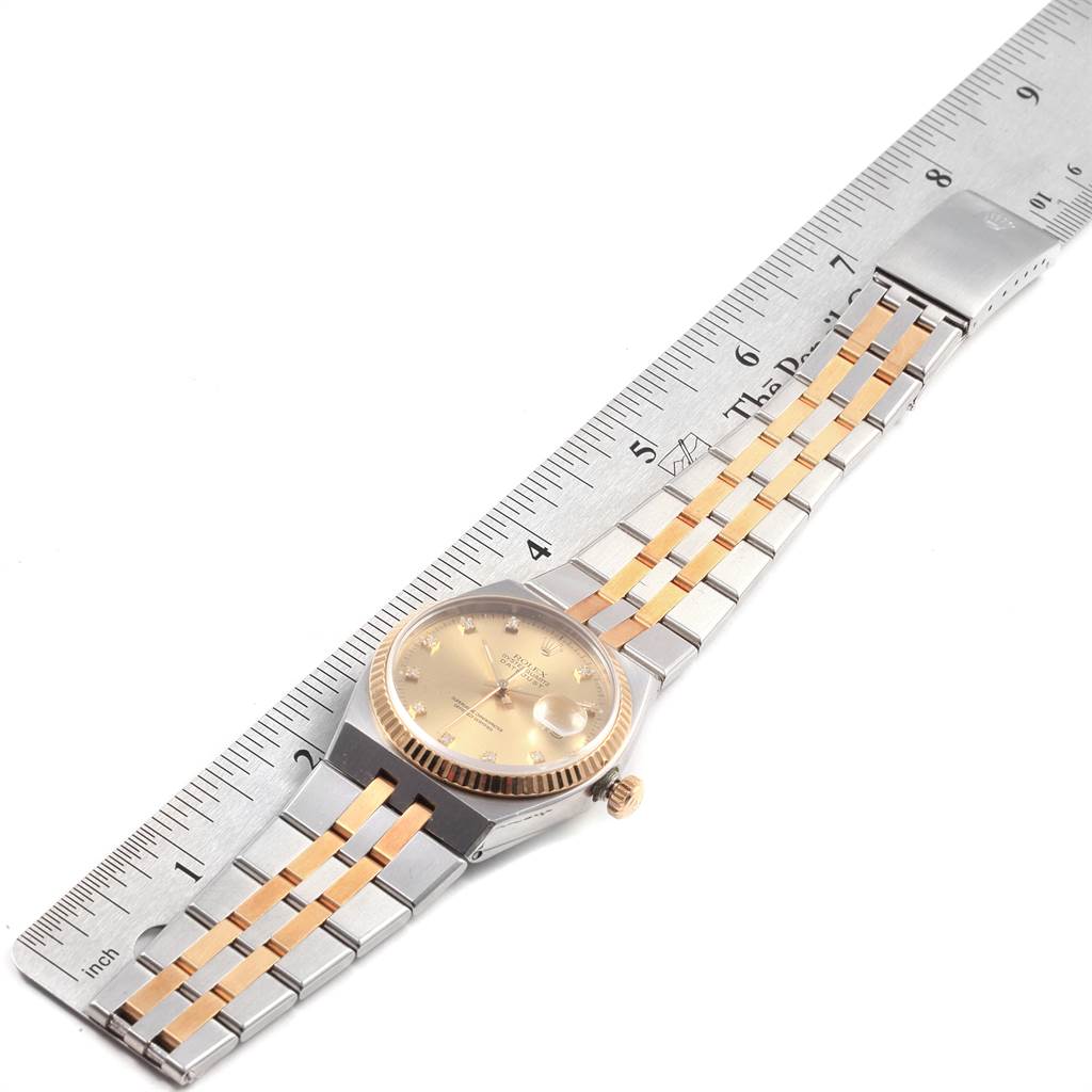 The image shows a Rolex Oysterquartz 17013 Men's Stainless Steel Champagne Dial 17013 Men's Stainless Steel Champagne Dial watch from a top-down angle, alongside a measuring ruler, highlighting the face, bezel, and bracelet.