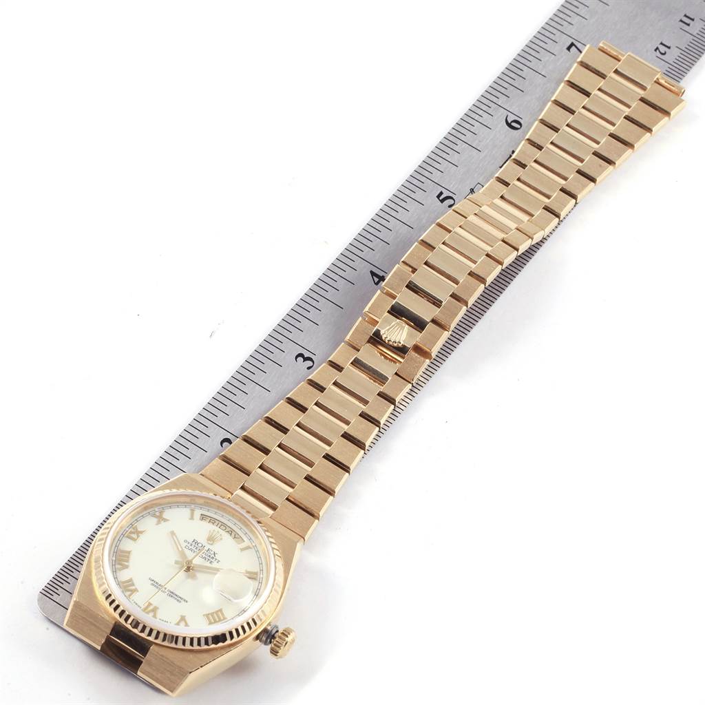 The Rolex Oysterquartz 19018 Men's Yellow Gold White Dial 19018 Men's Yellow Gold White Dial watch is shown from an angled top view, displaying the face, crown, and full bracelet on a ruler.