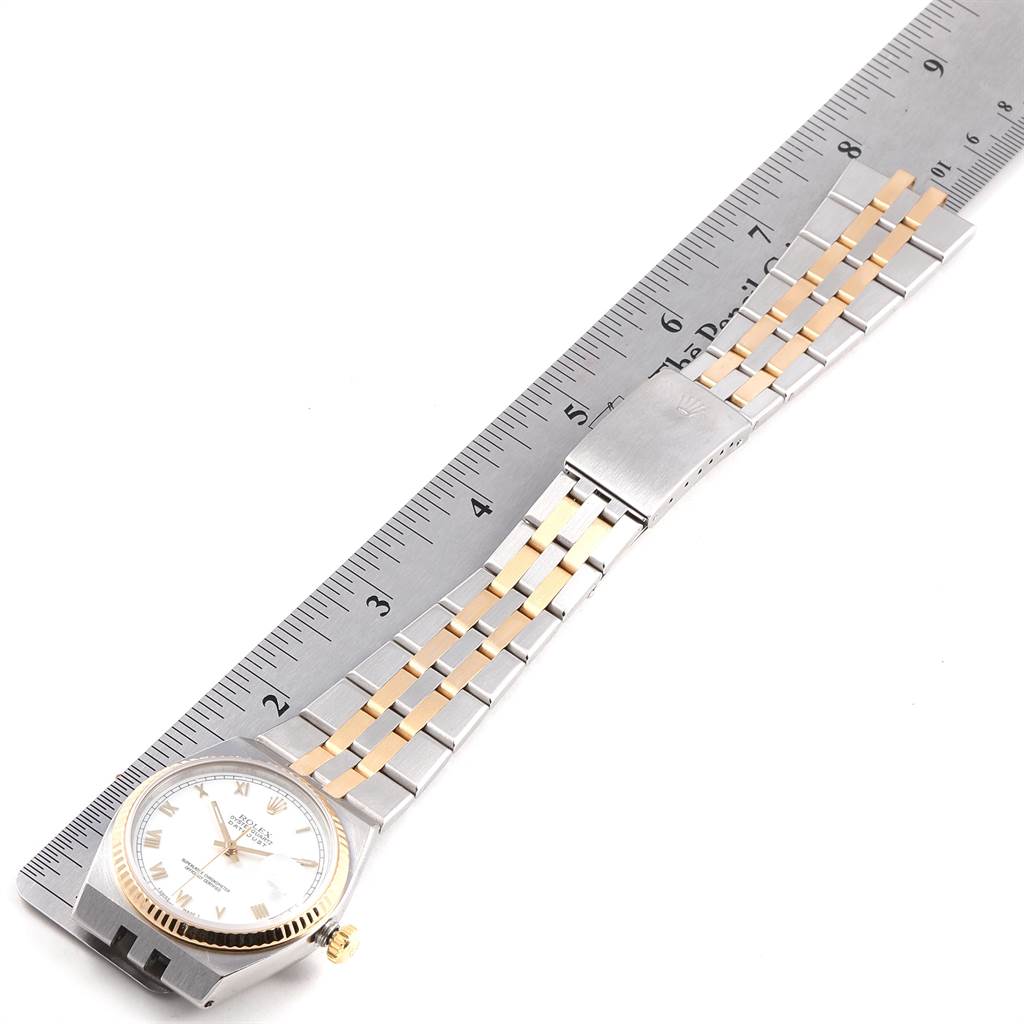 The Rolex Oysterquartz 17013 Men's Stainless Steel White Dial 17013 Men's Stainless Steel White Dial watch is shown laying flat with a focus on its dial, bezel, and two-tone metal bracelet, aligned alongside a ruler.