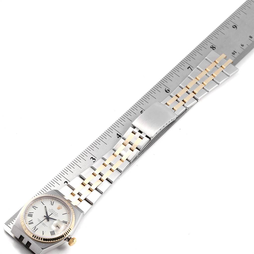 The Rolex Oysterquartz 19220 Men's Steel and Gold (two tone) White Dial 19220 Men's Steel and Gold (two tone) White Dial watch is shown from a top-down angle, displaying the face, bezel, and entire bracelet positioned alongside a ruler.