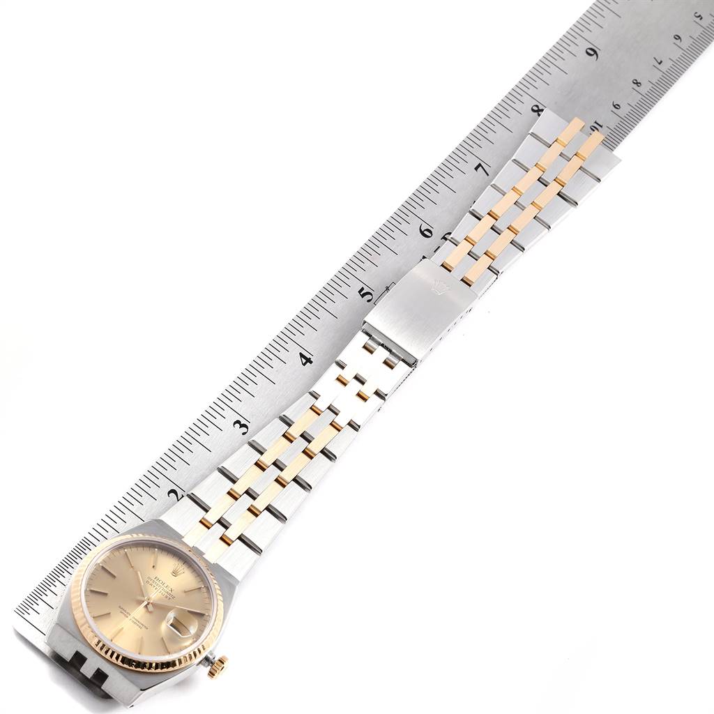 This image shows the Rolex Oysterquartz 17013 Men
s Stainless Steel Champagne Dial 17013 Men
s Stainless Steel Champagne Dial watch laid flat with its band extended along a ruler.