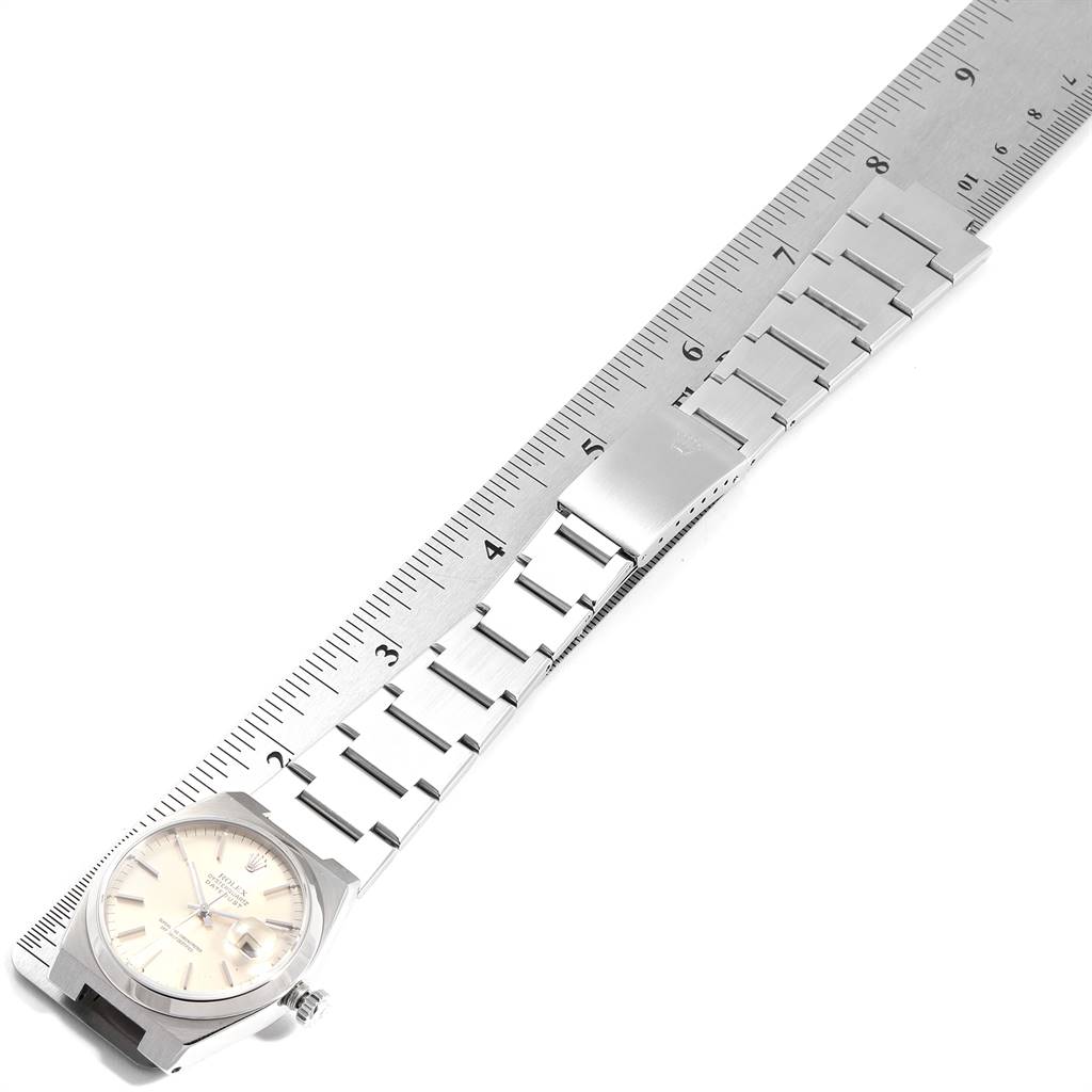 The Rolex Oysterquartz 17000 Men
s Stainless Steel Silver Dial 17000 Men
s Stainless Steel Silver Dial watch is shown from a top-down angle with its bracelet extended along a ruler.