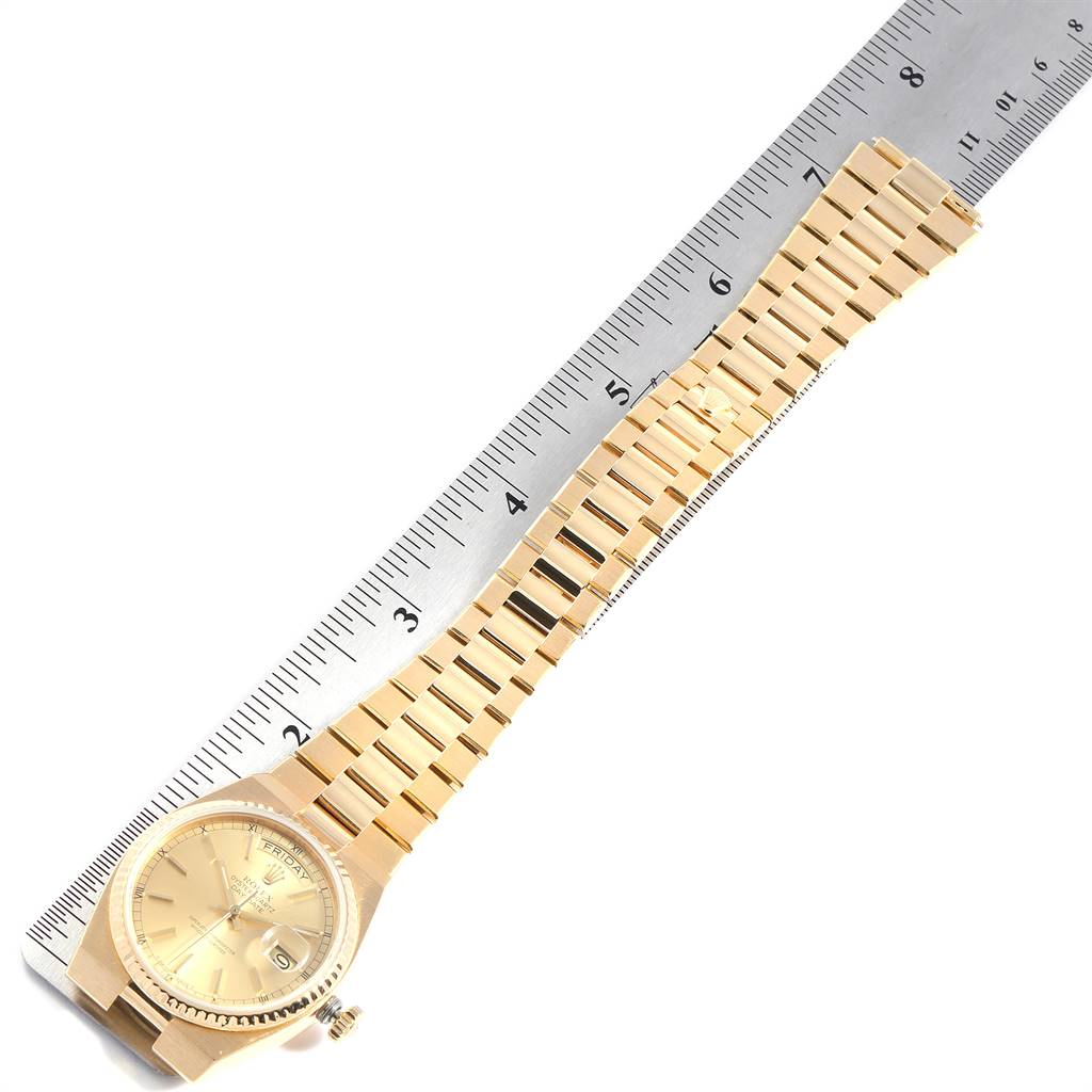 This image shows a Rolex Oysterquartz 19018 Men
s Yellow Gold Champagne Dial 19018 Men
s Yellow Gold Champagne Dial watch placed next to a ruler, displaying the watch face and entire gold bracelet.