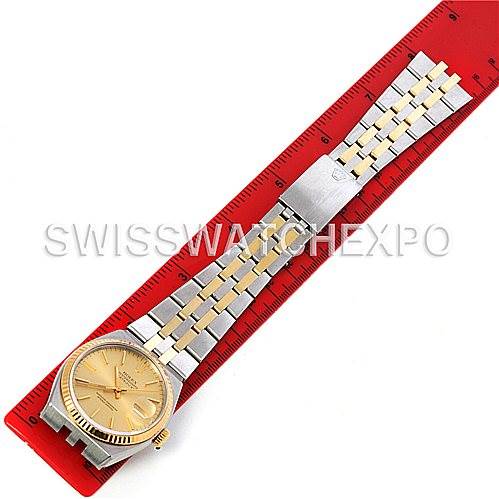 The Rolex Oysterquartz 17013 Men's Stainless Steel Champagne Dial 17013 Men's Stainless Steel Champagne Dial watch is shown from a top view, displaying the entire bracelet and face, placed next to a red ruler for measurement.