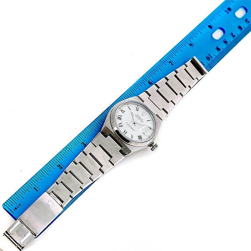 The image shows a top view of a Rolex Oysterquartz 17000 Men's Stainless Steel White Dial 17000 Men's Stainless Steel White Dial watch with a bracelet and a blue ruler beside it.