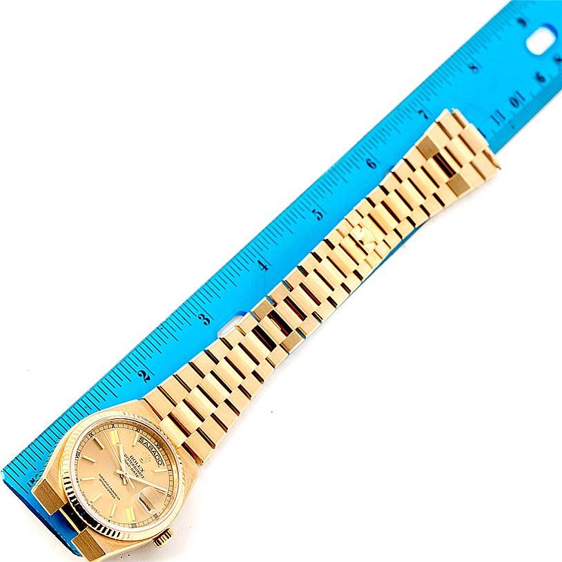 This image shows a top-down view of a Rolex Oysterquartz 19018 Men's Yellow Gold Champagne Dial 19018 Men's Yellow Gold Champagne Dial watch and its gold bracelet against a blue ruler for scale.