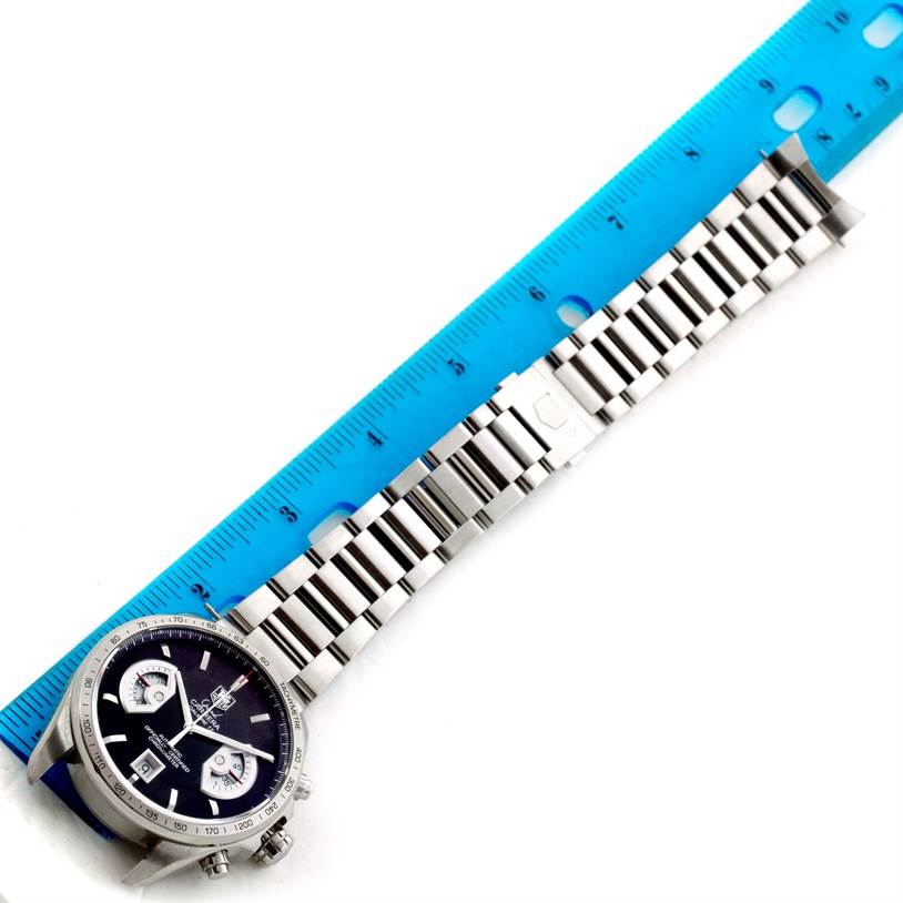 The Tag Heuer Carrera CAV511A Men's Stainless Steel Black Dial CAV511A Men's Stainless Steel Black Dial watch is shown from a top view, displaying the face, chronograph buttons, and metal bracelet alongside a measuring ruler.