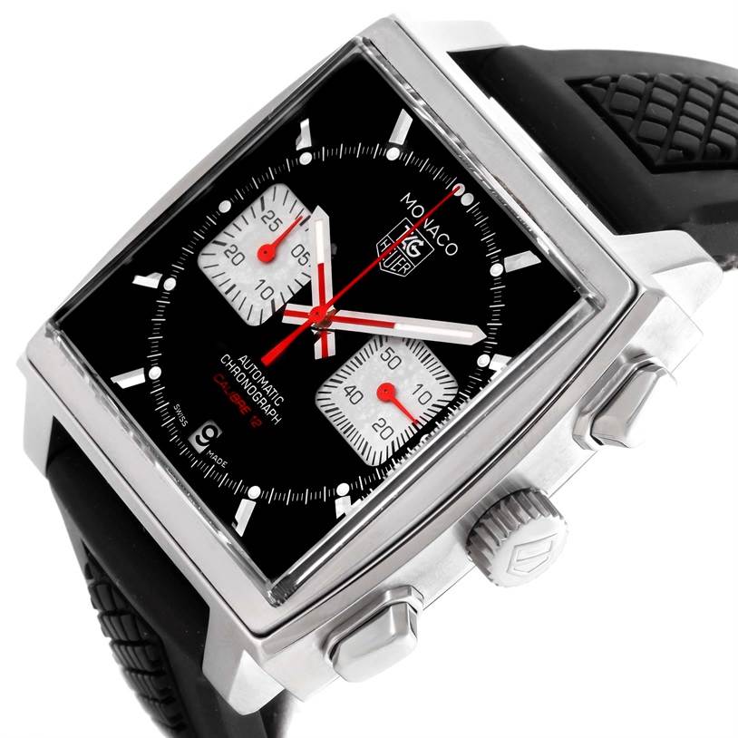 The image shows a Tag Heuer Monaco CAW2114 Men's Stainless Steel Black Dial CAW2114 Men's Stainless Steel Black Dial watch, highlighting its face at an angled view, crown, pushers, and black rubber strap.