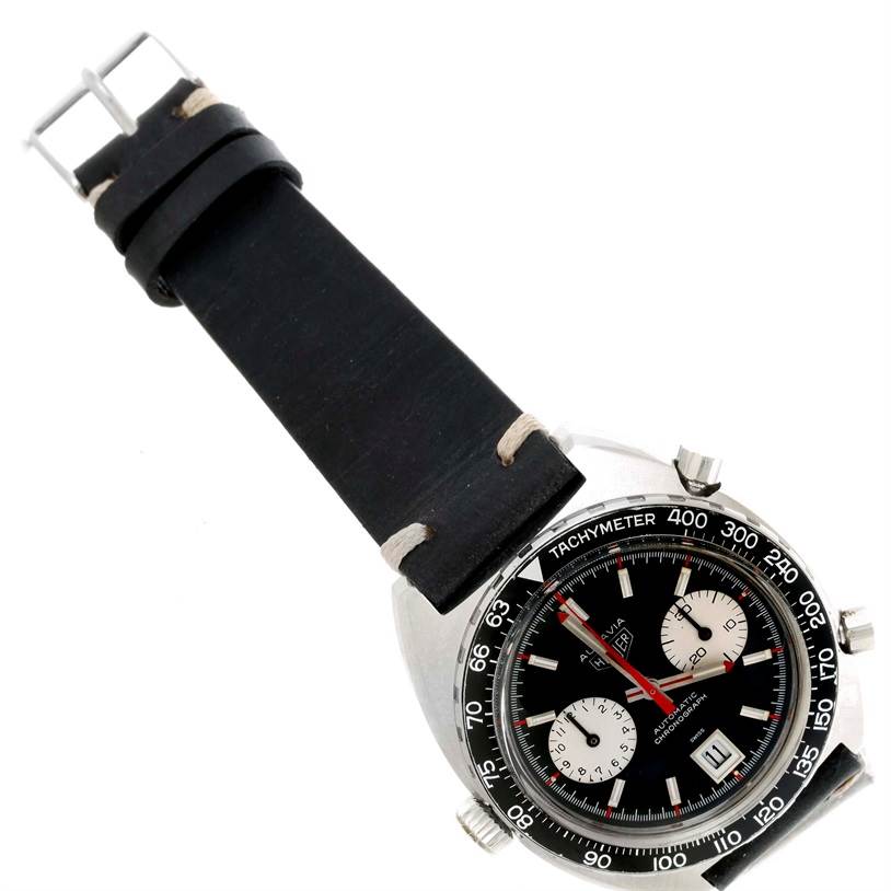 The image shows a Tag Heuer Autavia 1163 Men's Stainless Steel Black Dial 1163 Men's Stainless Steel Black Dial watch at an angled view, highlighting its face, tachymeter bezel, and black strap.