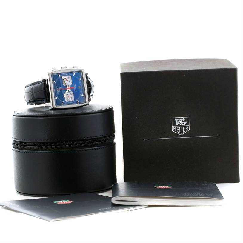 The Tag Heuer Monaco CW2113 Men
s Stainless Steel Blue Dial CW2113 Men
s Stainless Steel Blue Dial watch is displayed on a round black case, with its box and manuals beside it.