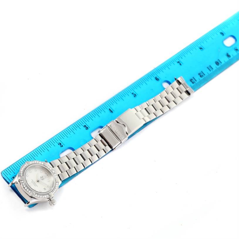 The image shows the Tag Heuer Aquaracer WAF1416.BA0824 Women's Stainless Steel Mother of Pearl Dial WAF1416.BA0824 Women's Stainless Steel Mother of Pearl Dial watch laid flat next to a blue ruler, emphasizing its dial and metal bracelet.