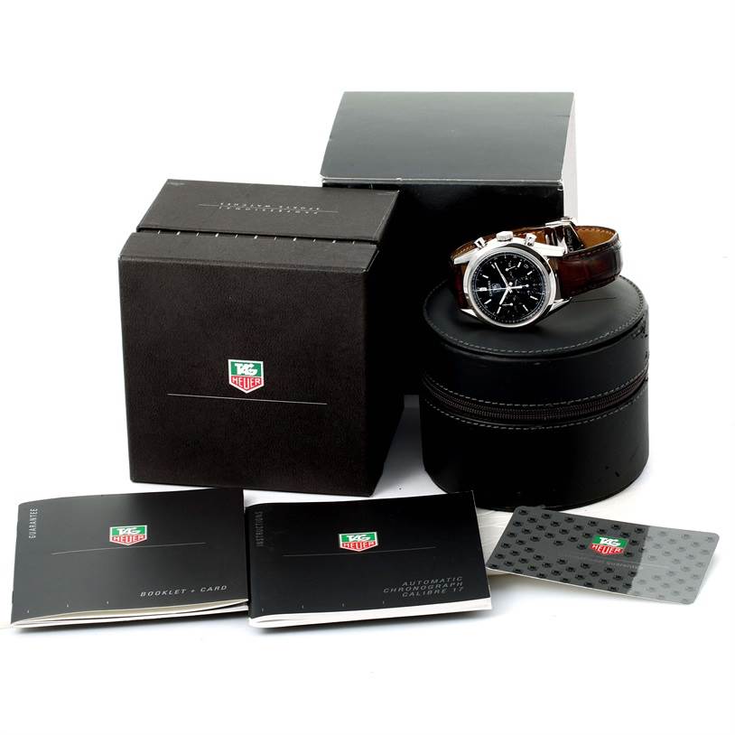 The image shows a boxed Classic model Tag Heuer watch with accessories including a cylindrical case, booklets, and a card.