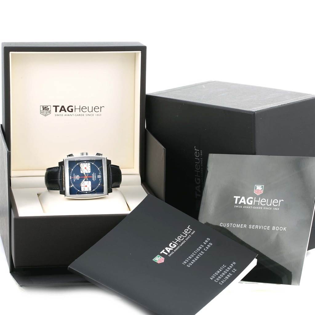 The image shows a Tag Heuer Monaco CAW2111 Men's Stainless Steel Blue Dial CAW2111 Men's Stainless Steel Blue Dial watch from a front angle, along with its box and manuals.